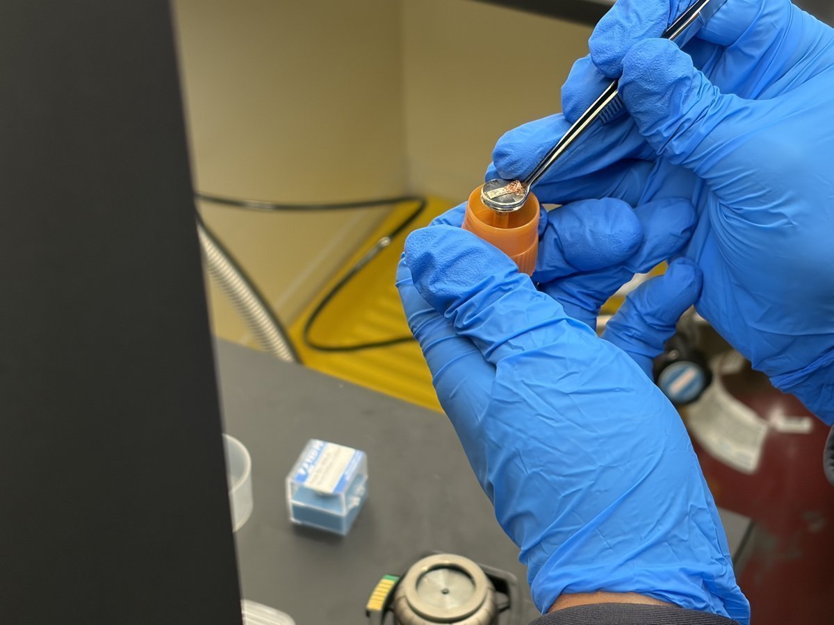 Lifting the new copper sample out of the orange-capped storage tube with tweezers