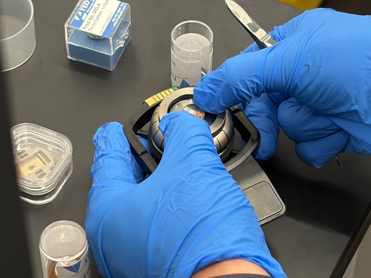 Pressing the copper wire sample down onto the stub with the thumb to secure it